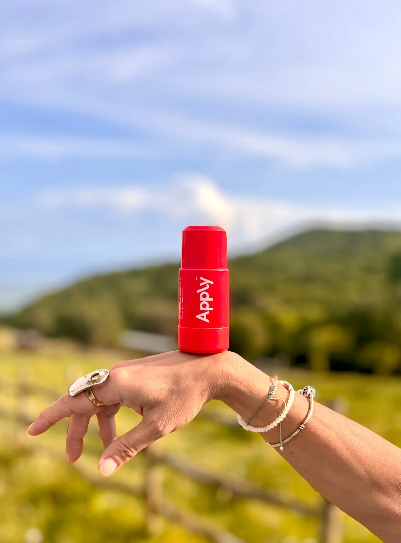 An Apply roll-on balanced on the back of a hand, hills behind