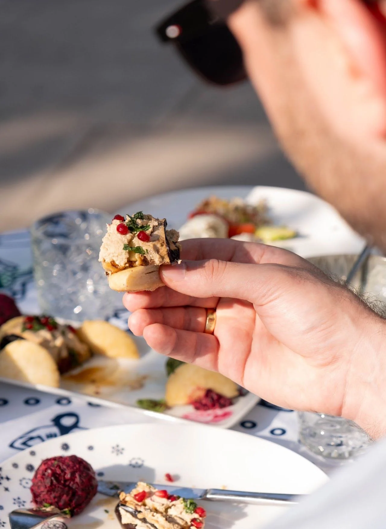 A guest holds up a small bite at an outdoor table