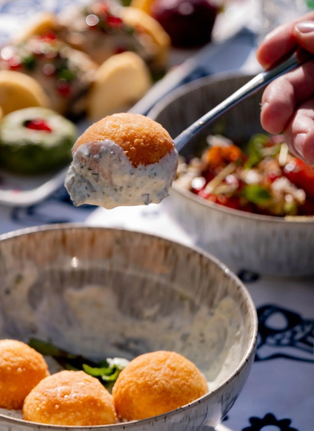 A fried ball lifted on a spoon from its creamy sauce