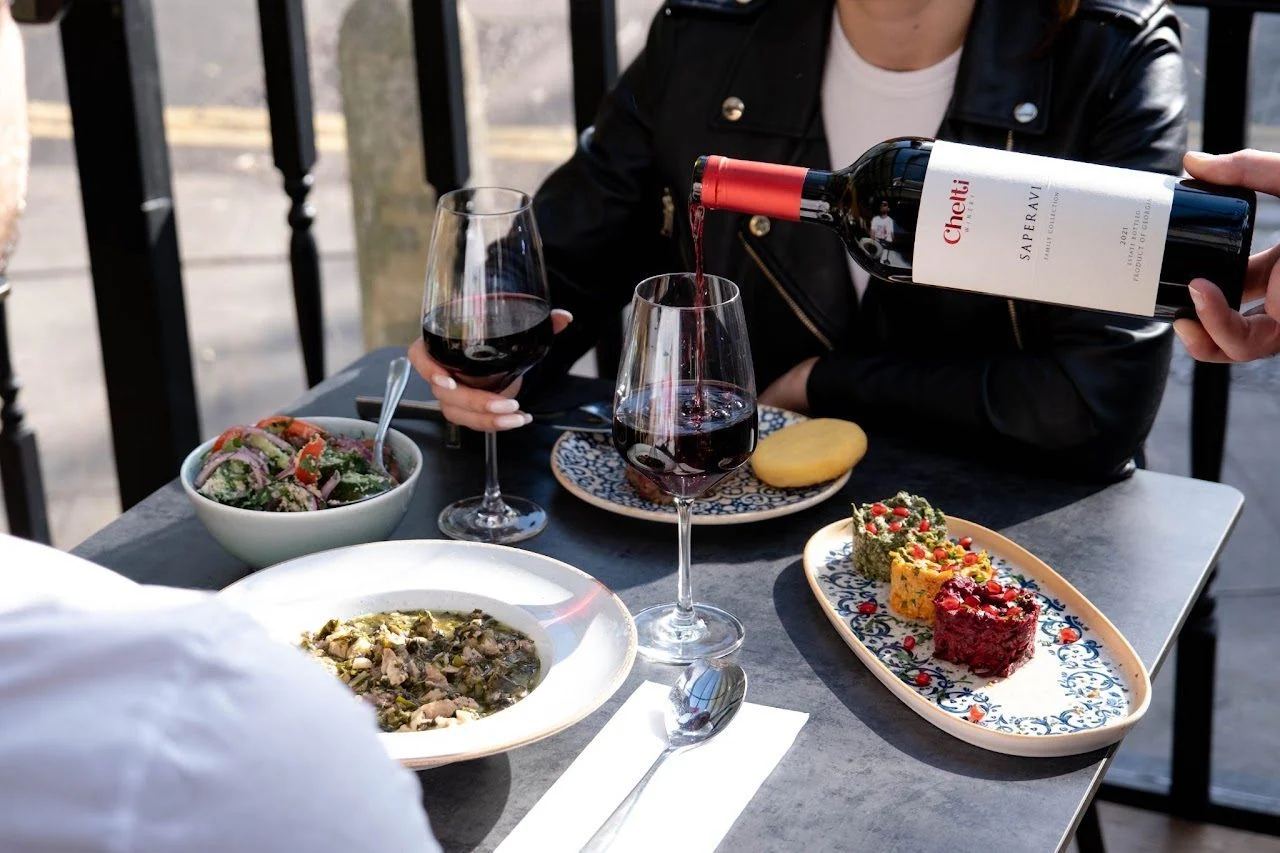 Red wine poured at a table of Georgian dishes at Gurmani